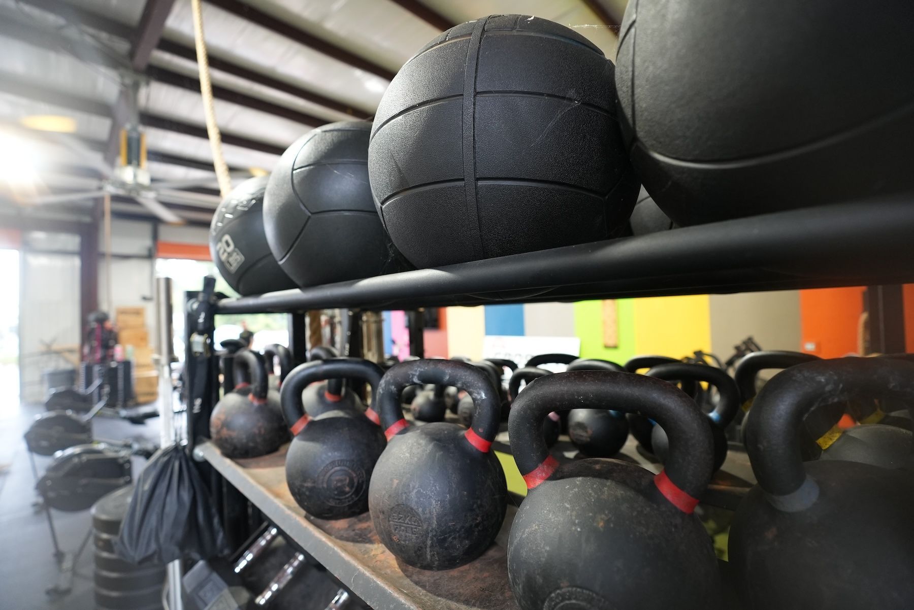 A row of kettlebells and medicine balls on a shelf at CrossFit Threshold gym
