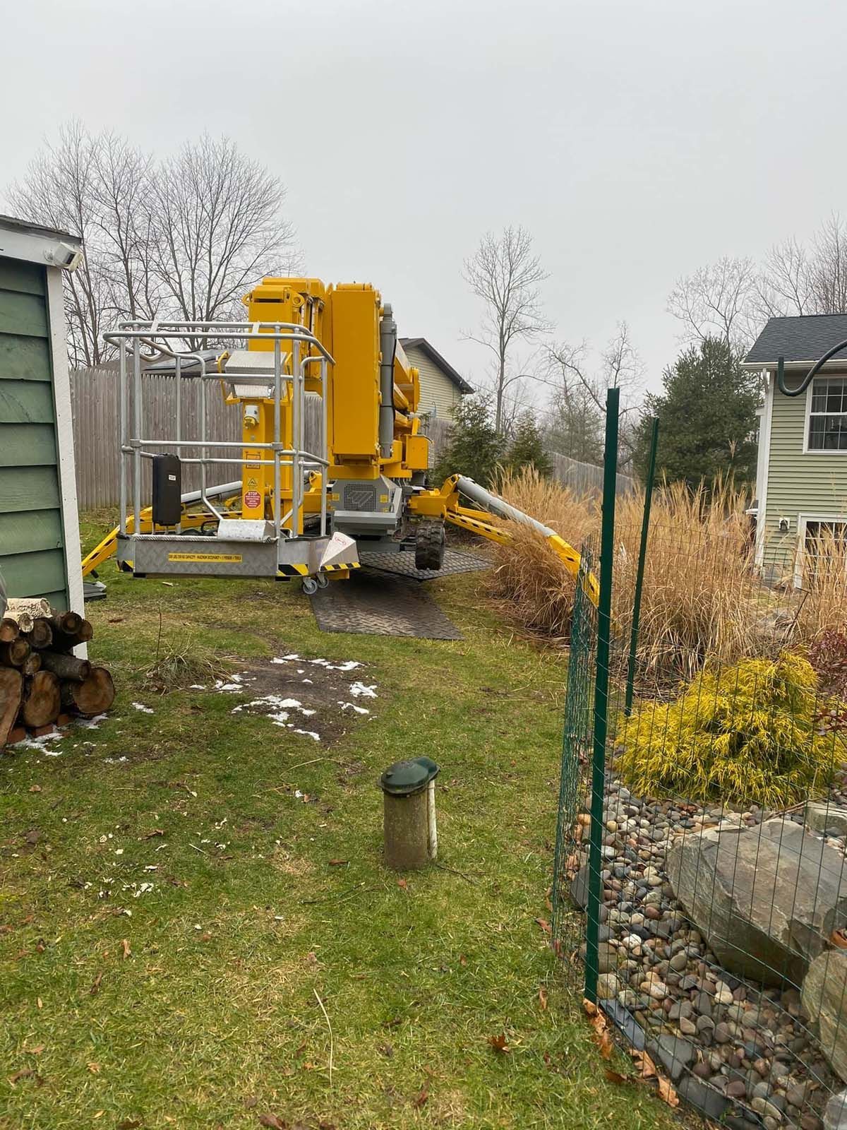 A yellow crane is parked in the backyard of a house.