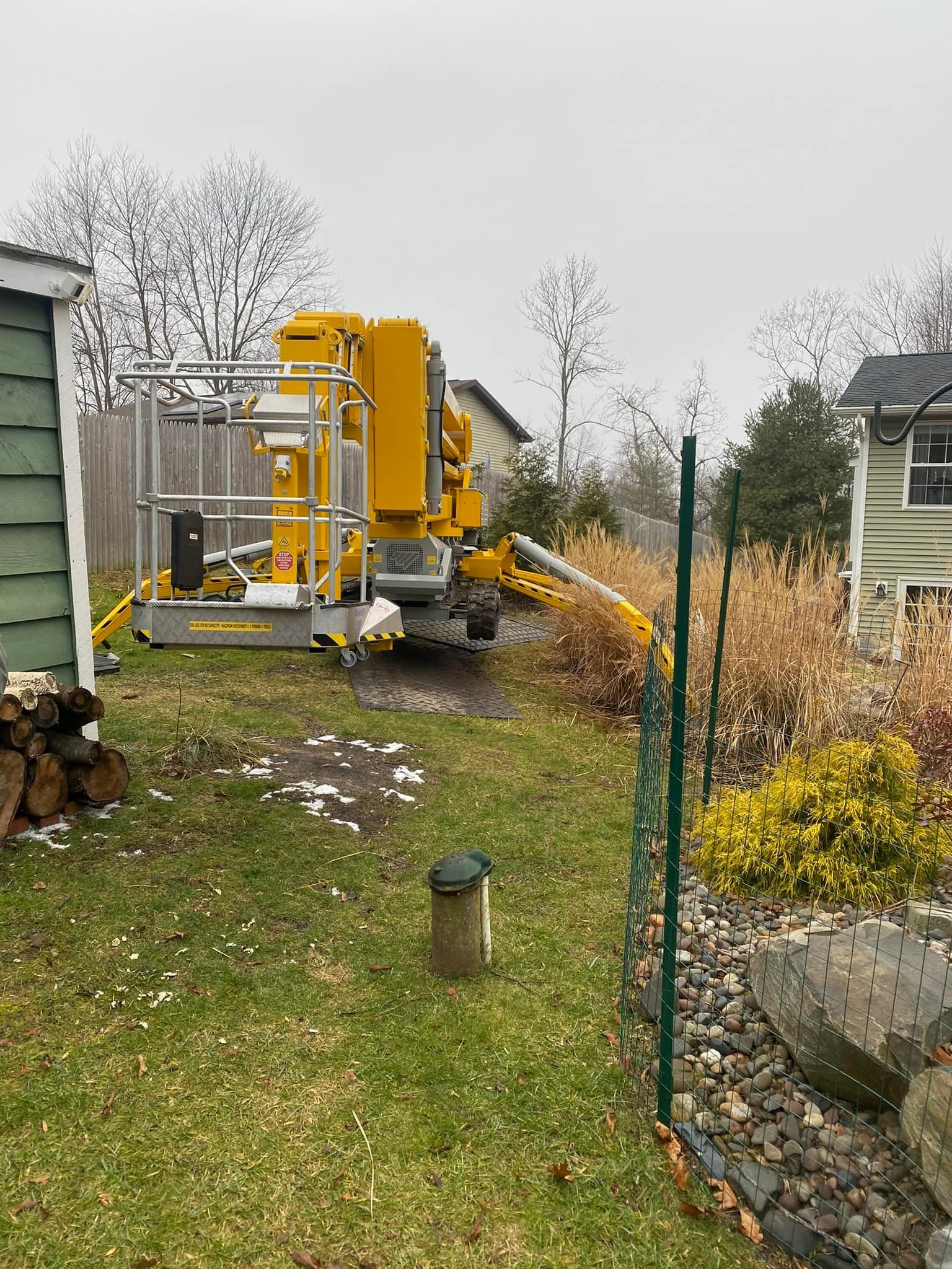 A yellow crane is sitting in the backyard of a house.