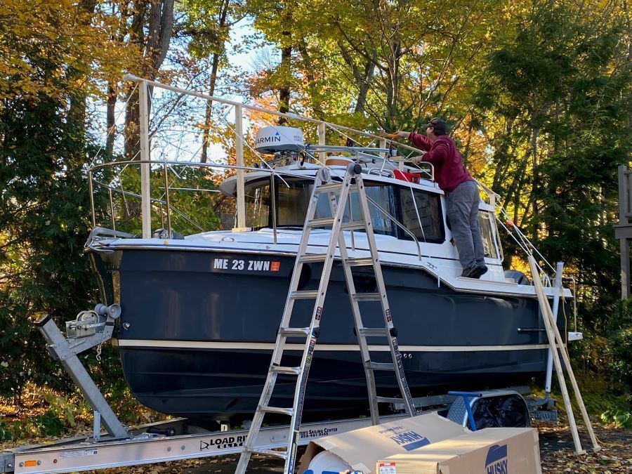 A man is standing on a ladder next to a boat.