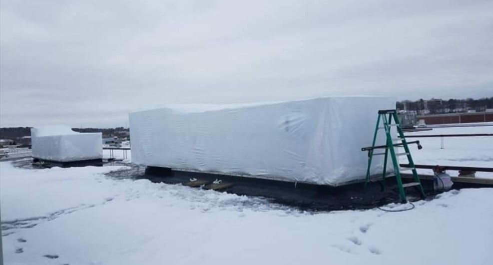 A large piece of ice is sitting on top of a snow covered field next to a ladder.