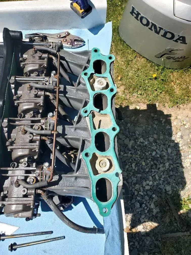 A boat engine is sitting on a table next to a honda bucket.