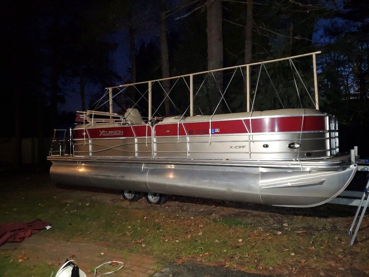 A pontoon boat is parked in the grass at night