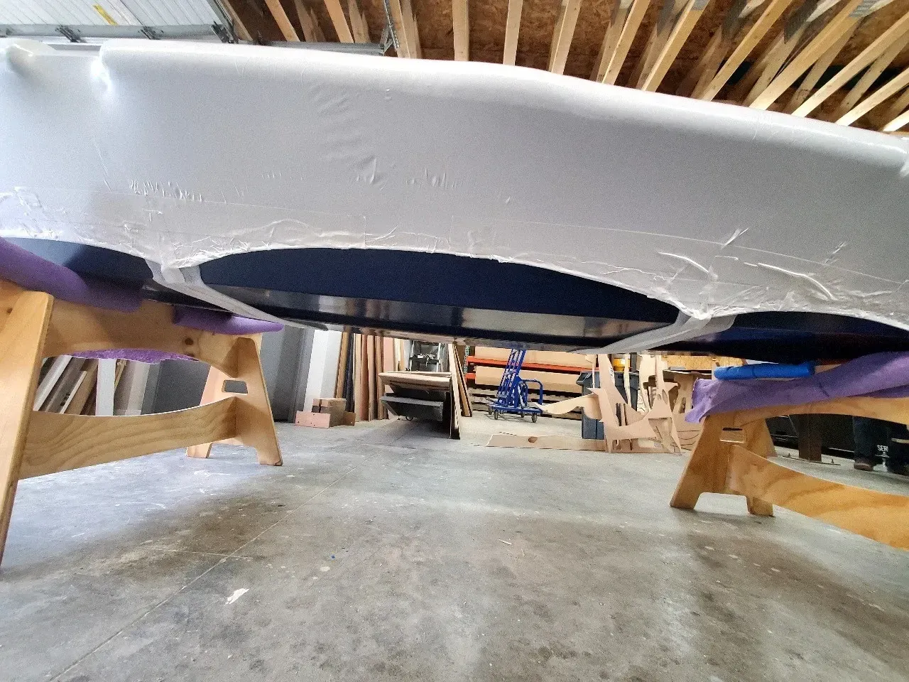 A pool table is sitting on a wooden stand in a garage.