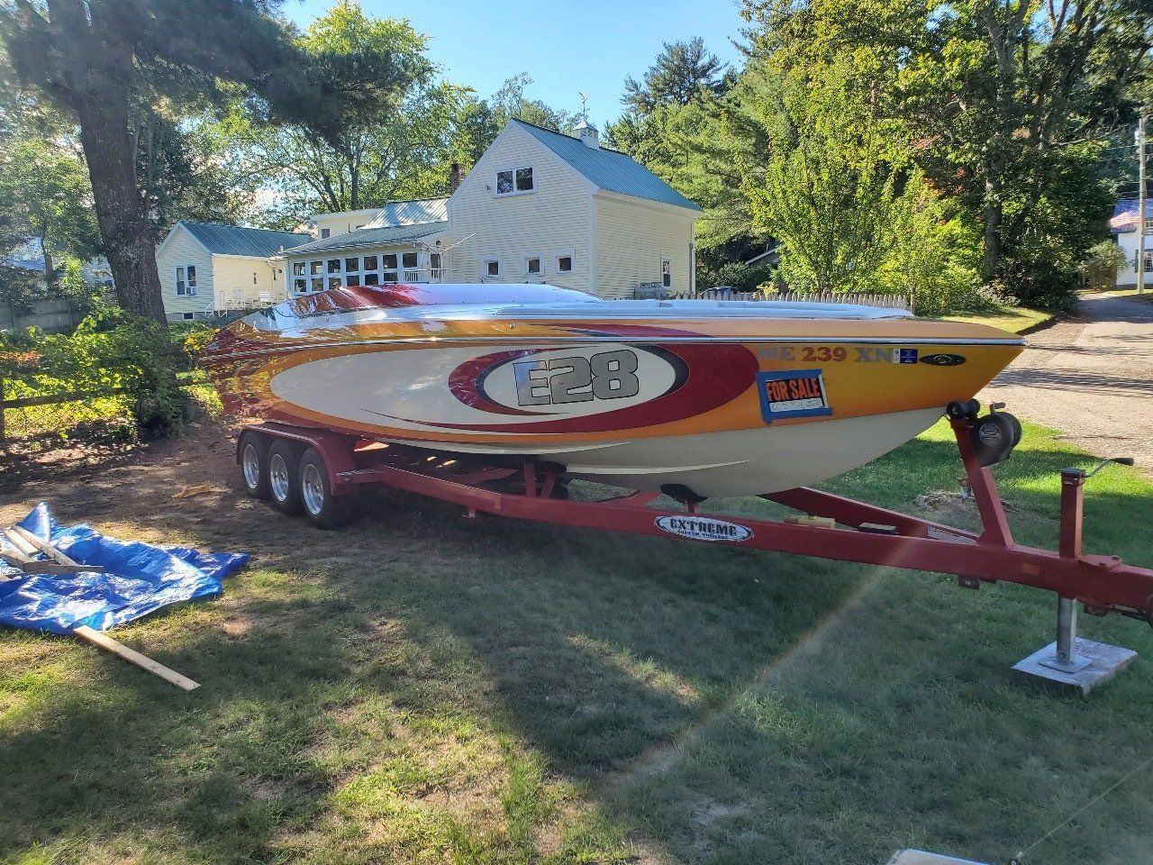 A boat is parked on a trailer in front of a house.
