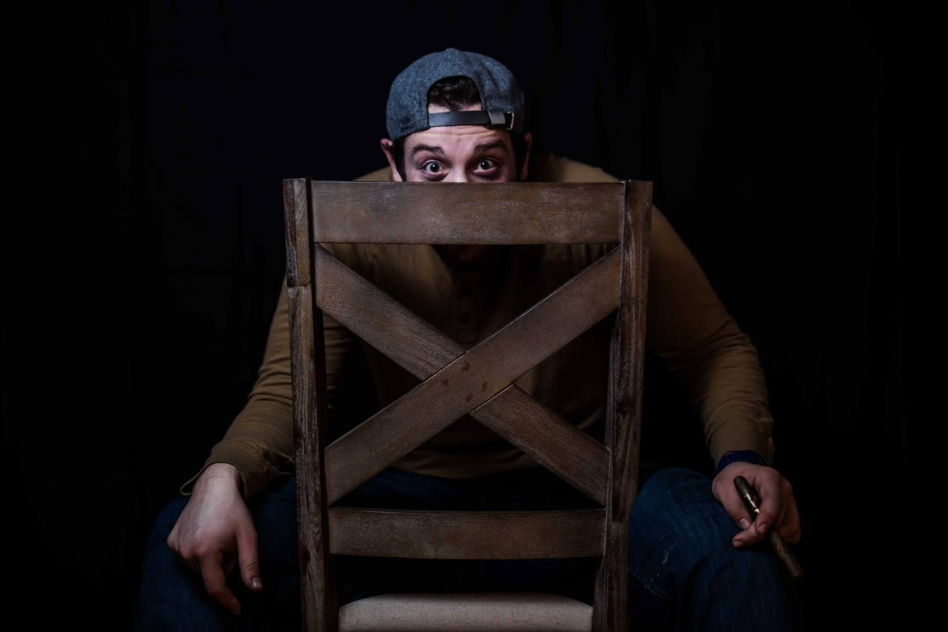 a man sitting in a chair with his face behind the back of the chair