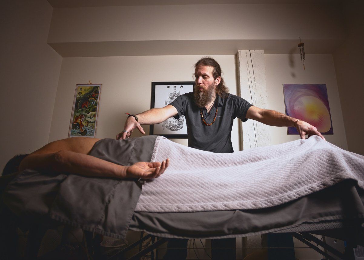 A man is standing next to a woman laying on a massage table.