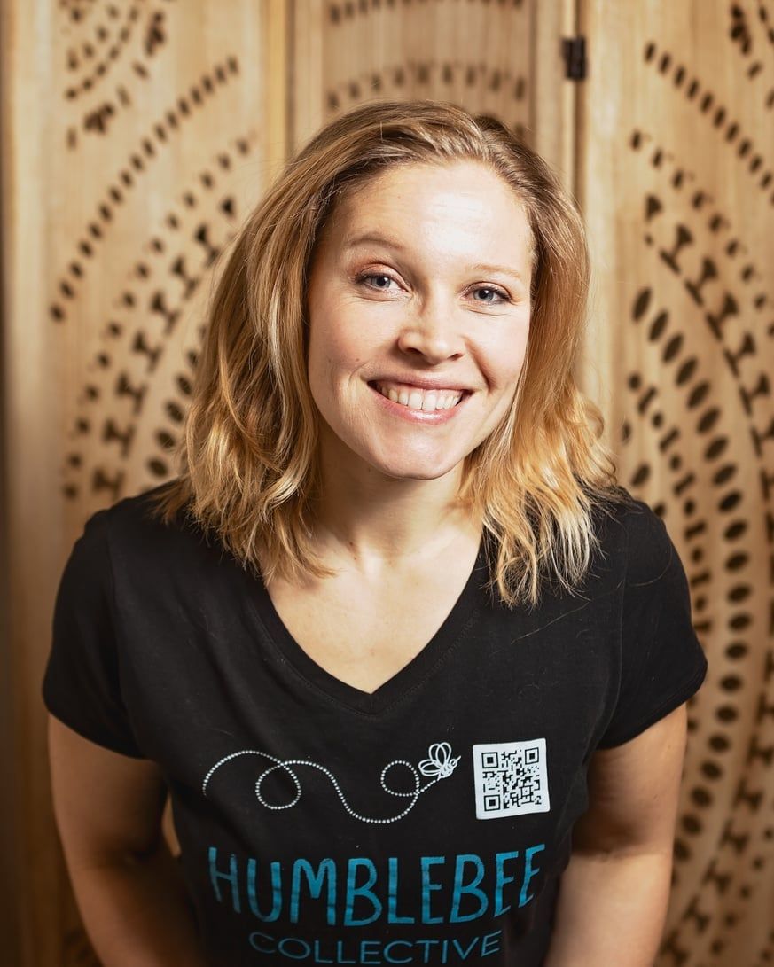 A woman is wearing a black t-shirt and smiling.