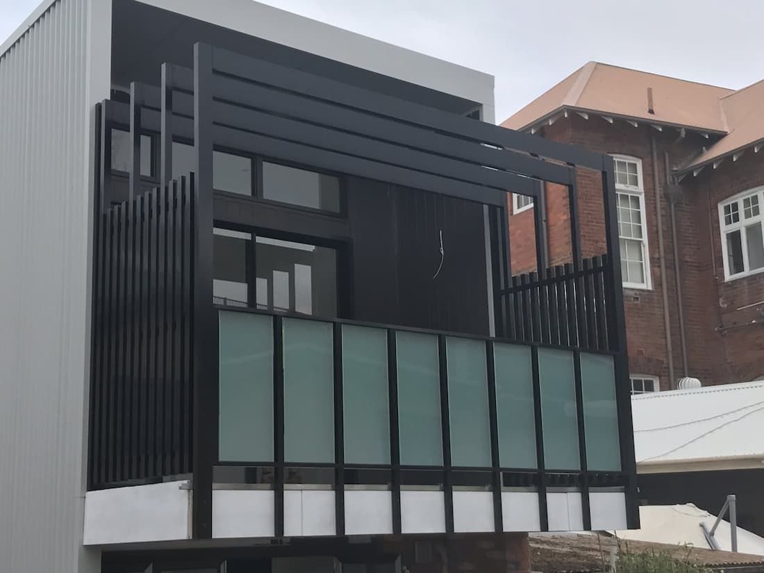 Balcony With A Black Railing And Glass Panels - Glass Balustrade in Newcastle, NSW