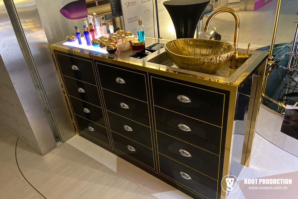 A stylish black and gold vanity with a gold sink and drawers filled with beauty products.