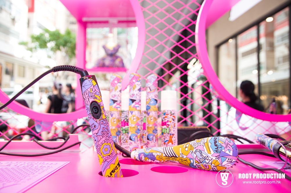 Pink cosmetic display with patterned hair dryers and perfume bottles.