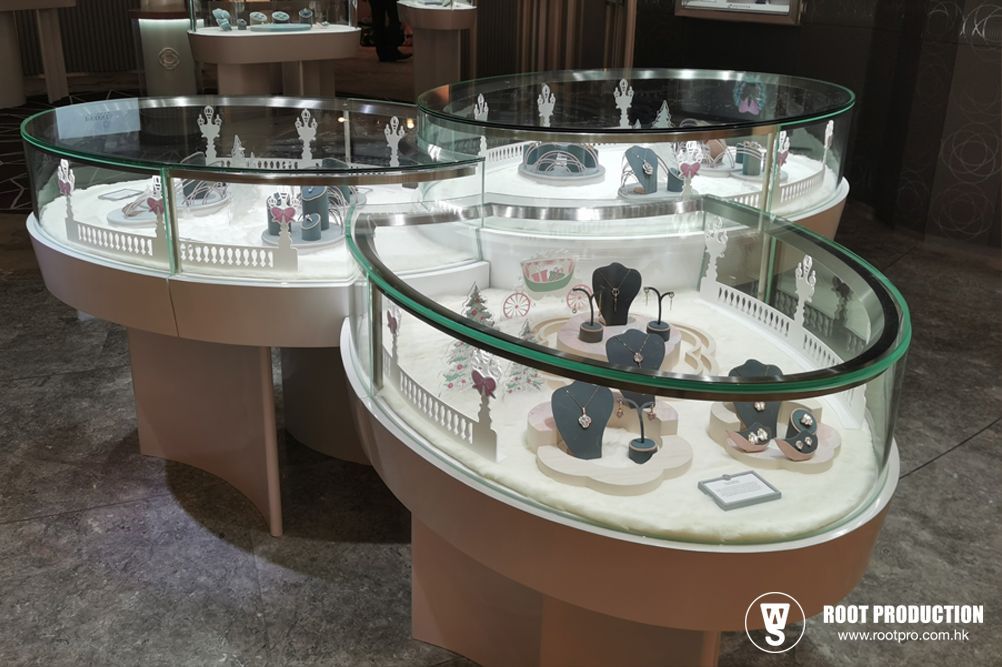 Three oval jewelry display cases, white with glass tops, showing various necklaces and earrings.