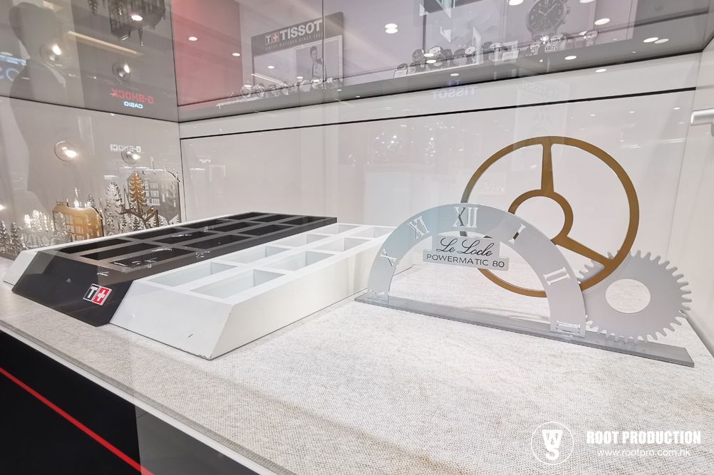 Display case with watch trays and a clock design element in a shop.