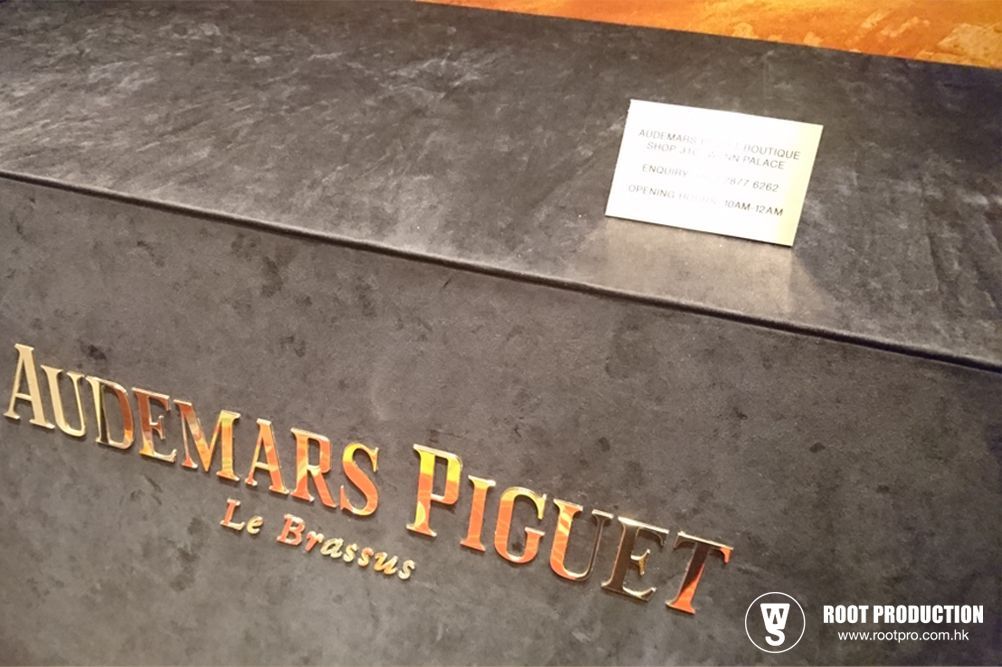 Close-up of Audemars Piguet box with gold lettering and a small card on a dark surface.