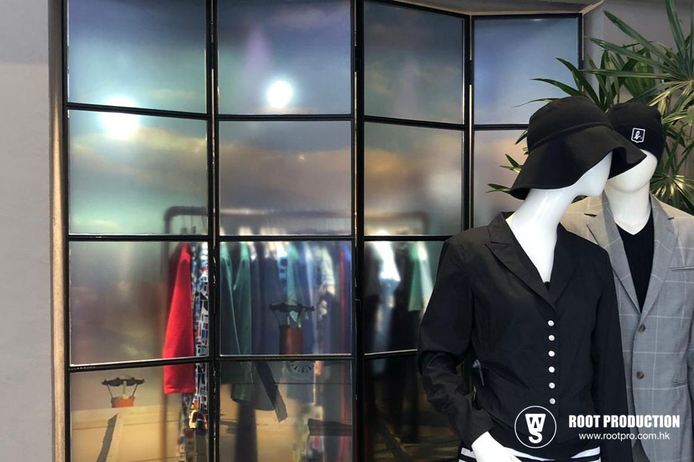 Mannequins in a clothing store window display behind frosted glass. Clothing racks visible.