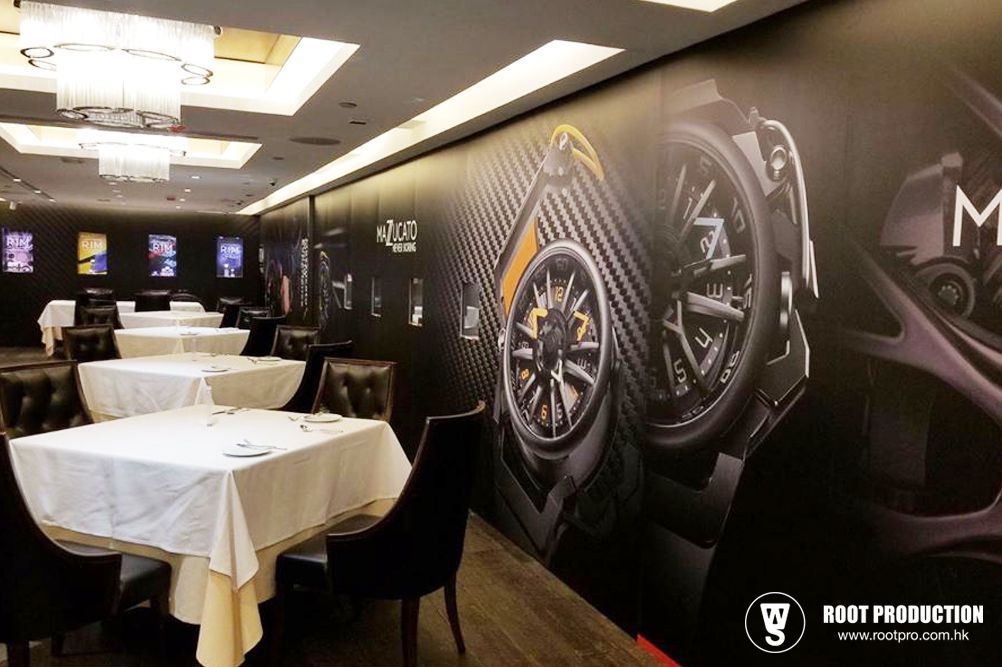 Restaurant interior with black walls, watch advertisements, and tables set for dining.