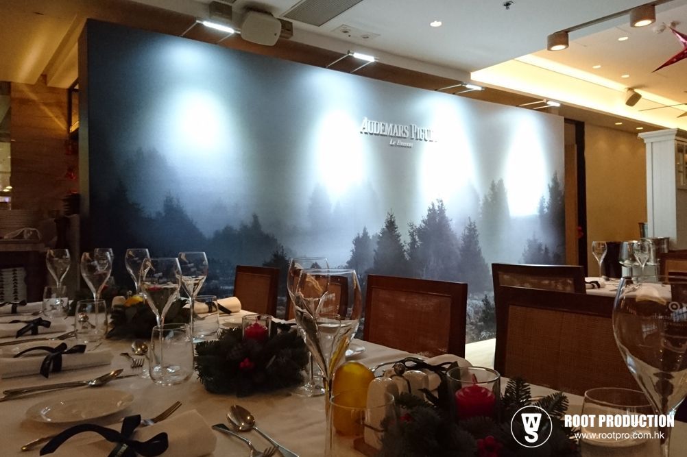 Formal dining table set before a backdrop of a foggy forest, likely for an event.