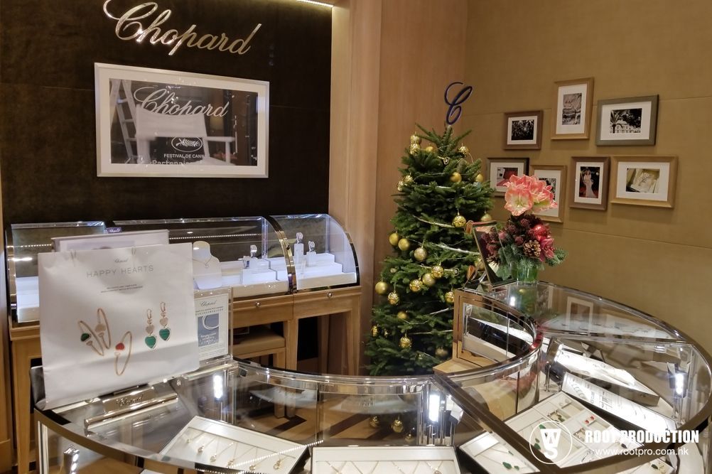 Jewelry store with glass display cases, Chopard sign, Christmas tree, and shopping bags.