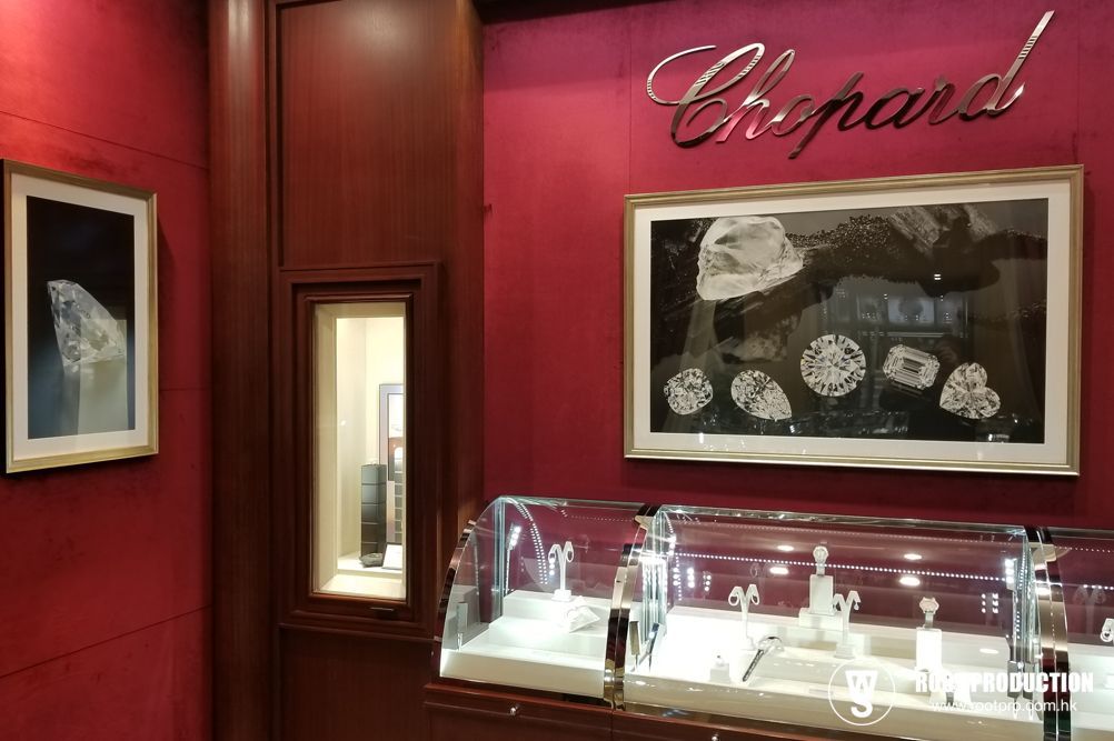 Inside a Chopard jewelry store: red walls, display cases with jewelry, artwork, wood trim.