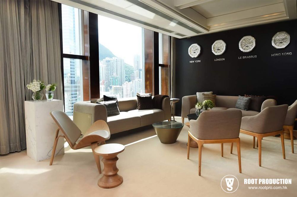 Modern lounge with city views, gray sofa and chairs, black wall with clocks.