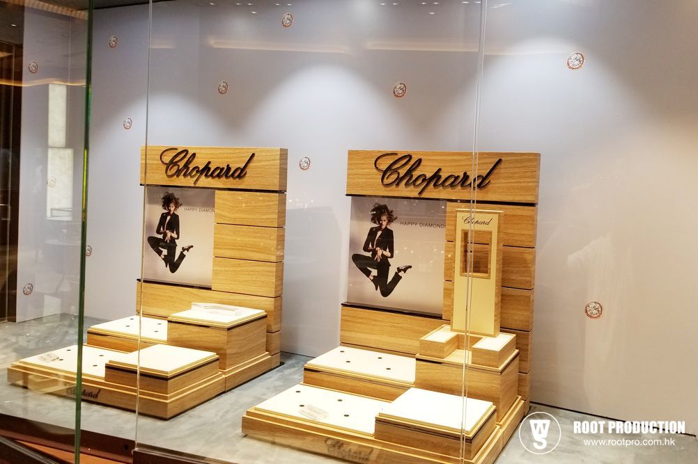Wooden display cases in a shop window, featuring the Chopard logo and merchandise.
