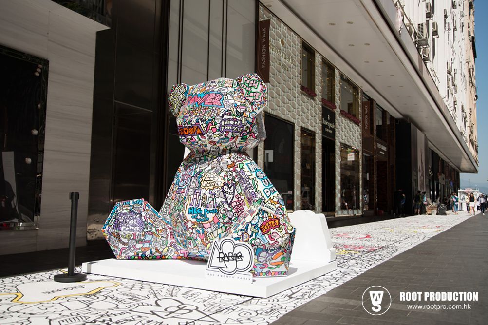 Large, sticker-covered teddy bear sculpture displayed outside a building.