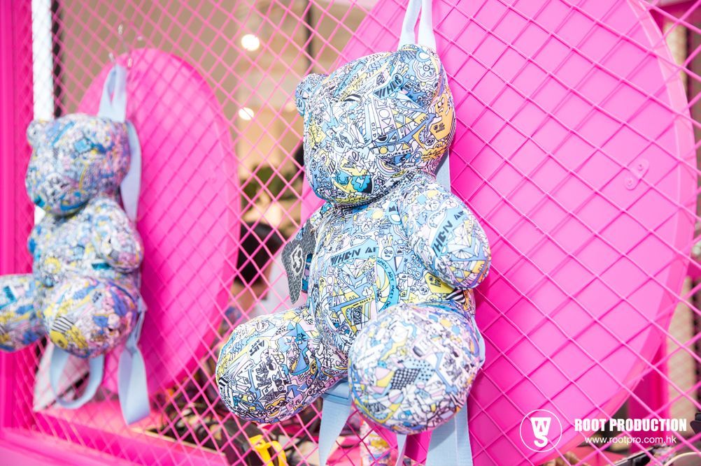Two fabric teddy bears with blue floral patterns, hanging against a pink grid background.