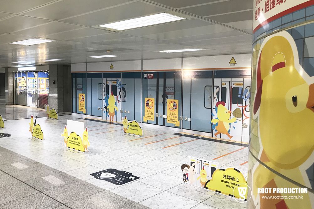 Subway station platform with yellow cartoon characters, temporary barriers, and closed train doors.