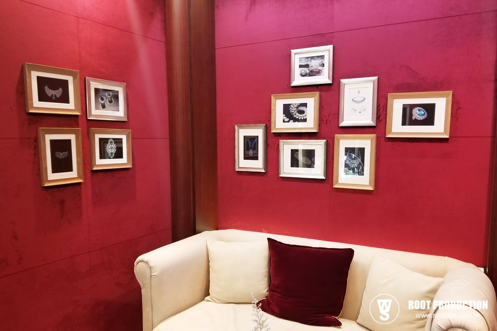 A gallery of framed photos on a red wall above a white sofa with a burgundy pillow.