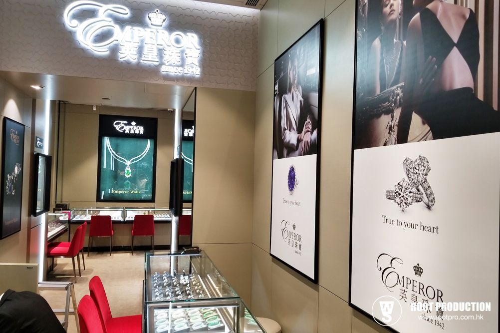 Interior of an Emperor jewelry store with displays and posters. Red chairs, white logo, and jewelry cases.