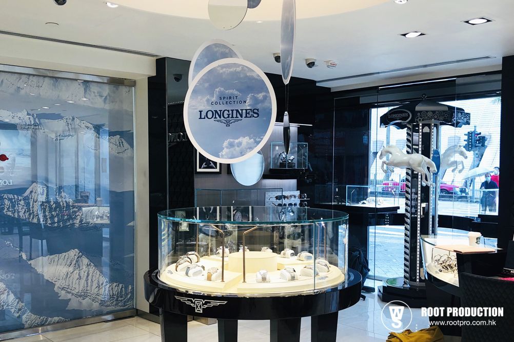 Inside a Longines watch store, a circular display case showcases watches. Decorations include blue cloud accents.