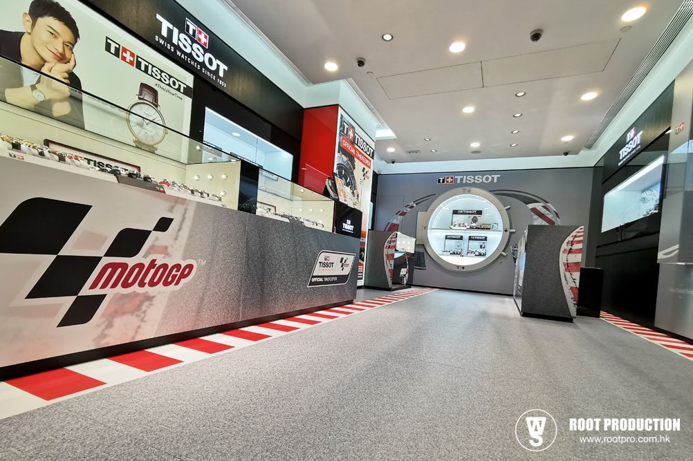 Tissot watch store with MotoGP branding; displays watches on a race track-themed floor and counters.