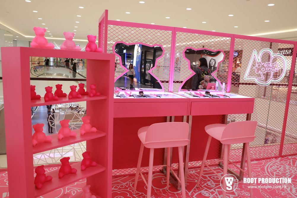 Pink retail pop-up with bear decor, counters, stools, and display shelves in a mall setting.
