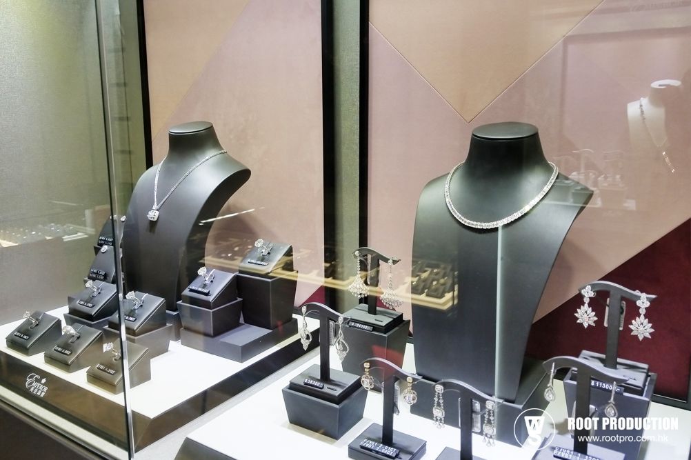 Jewelry display case with necklaces, earrings, and rings on black mannequins, inside a store.