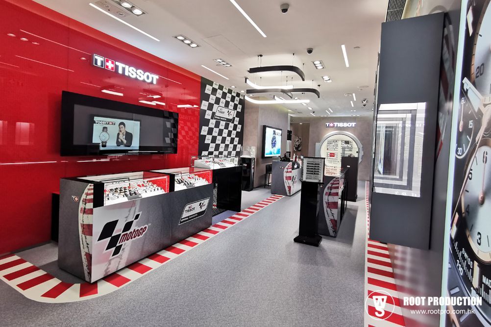 Tissot watch store interior with red accents and checkered flag theme, displaying watches and promotional screens.