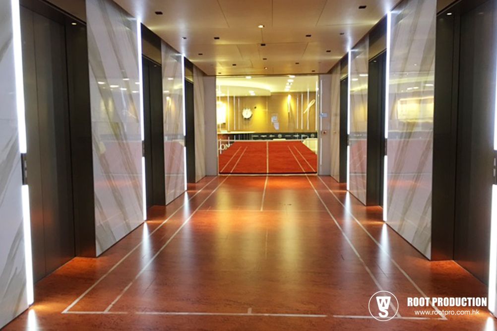 Hallway with running track flooring, leading to a red track. Elevators on either side.