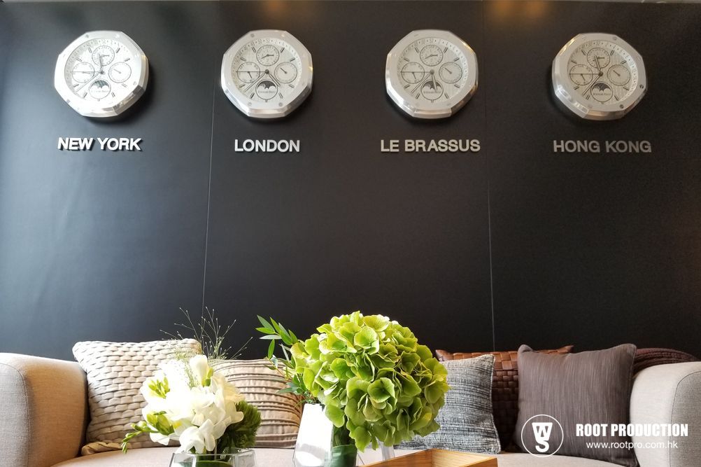 Four clocks displaying different time zones above a sofa with flowers.