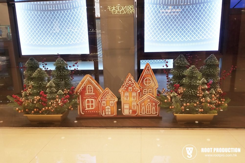 Christmas storefront display with gingerbread houses and snow-covered trees.