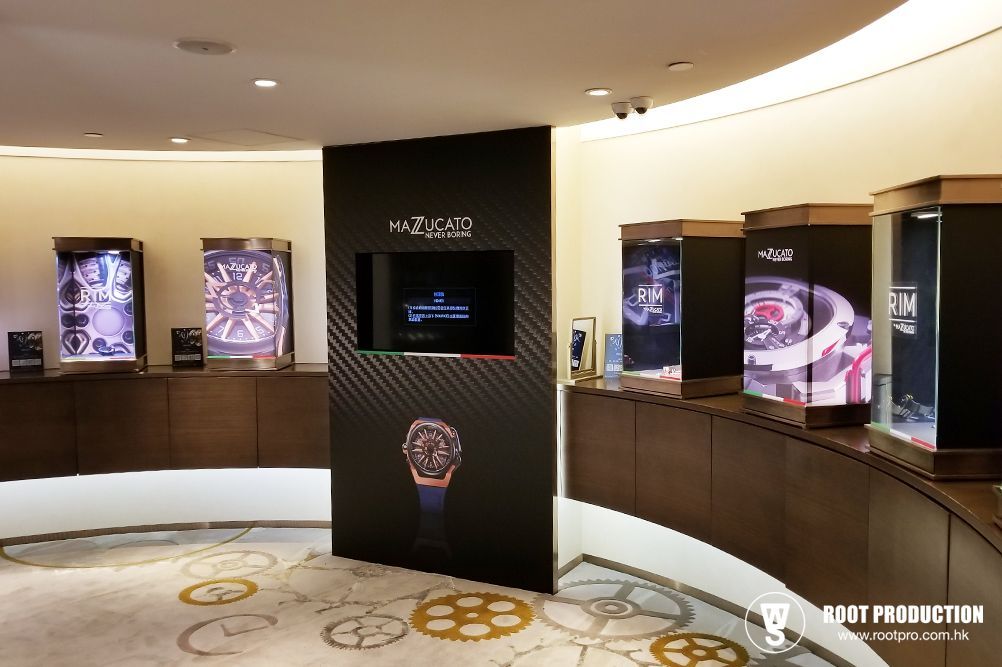 Watch display in a store, showcasing luxury timepieces on dark wooden shelves with decorative floor patterns.