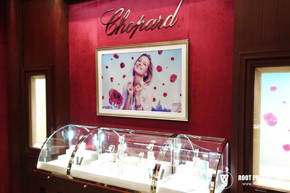 Chopard jewelry display with a photo of a woman surrounded by pink flowers, and a red wall backdrop.