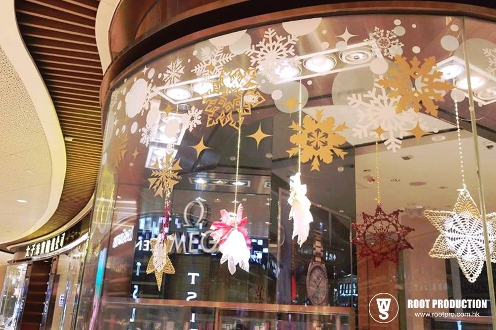 Holiday window display with gold and white snowflakes and hanging ornaments.
