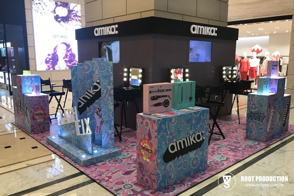 Amika hair product display in a mall. Features cosmetic tools, colorful boxes, and illuminated stands.