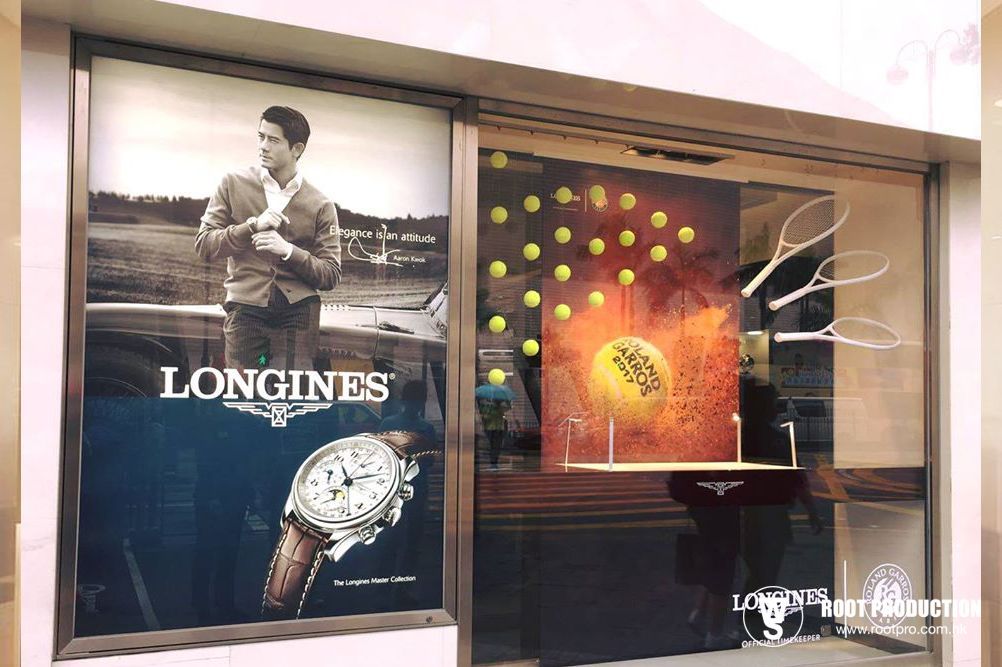 Window display: Longines watch ad with man, watch, and tennis ball art.