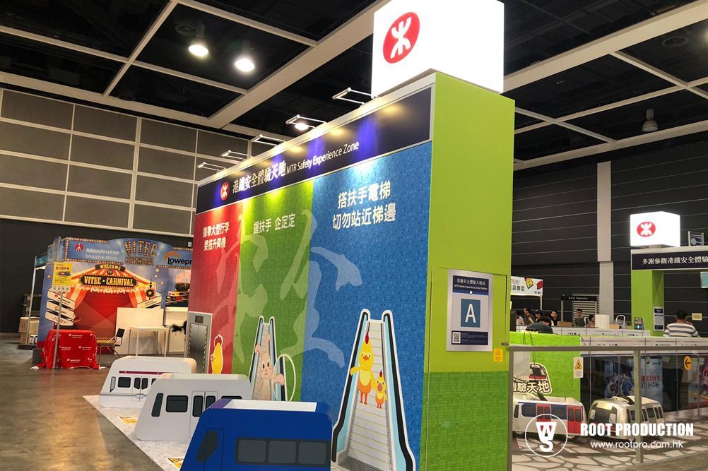Exhibition booth with MTR logo and Chinese text, featuring colorful panels and train models, in a convention hall.