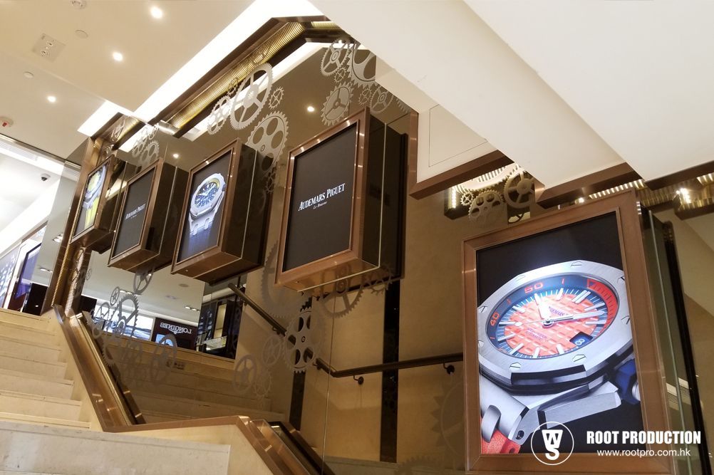 Upscale retail interior with watch displays. Staircase with backlit watch advertisements, steampunk-style decor.