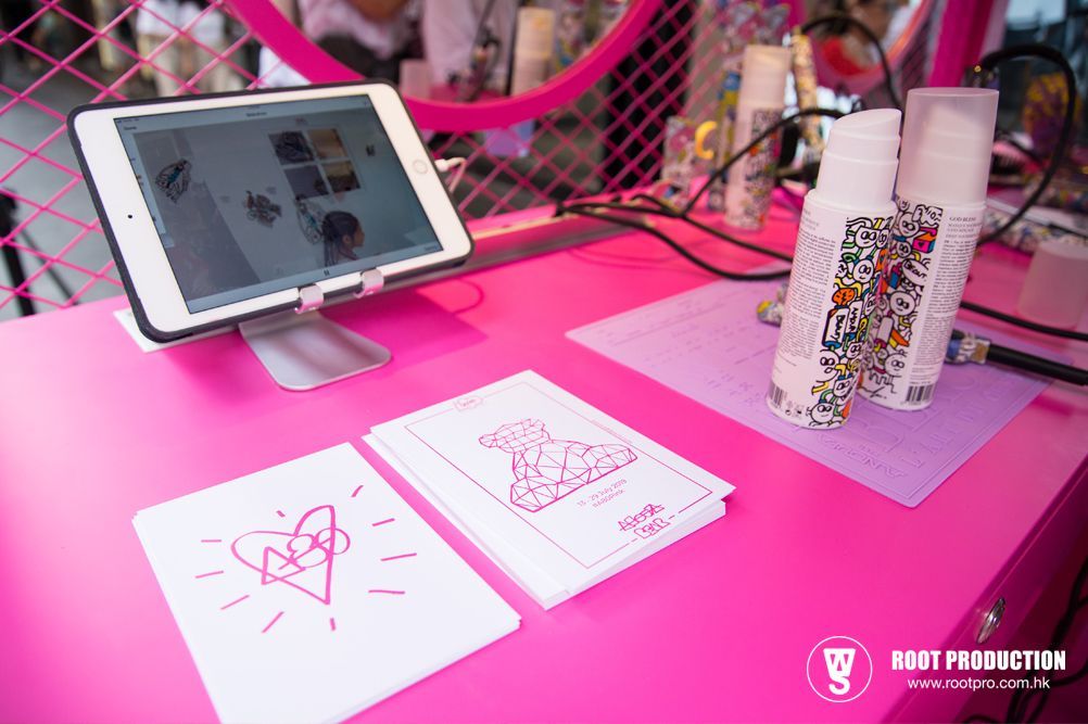 Pink table with iPad, spray bottles, and printed material.