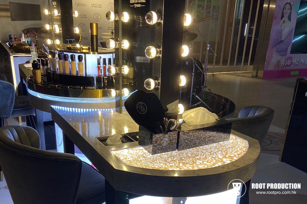Makeup station with illuminated mirror, products, and seating.