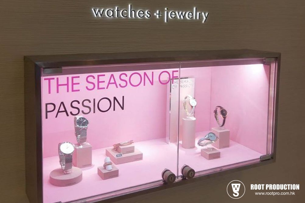 Jewelry display case with watches on pink pedestals. Text says 