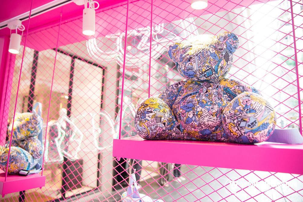 Pink-themed storefront with a large patterned teddy bear on a shelf, other sculptures and wire details.