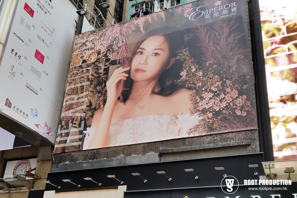 Billboard featuring a woman in a floral gown, holding her hand near her face, with a 